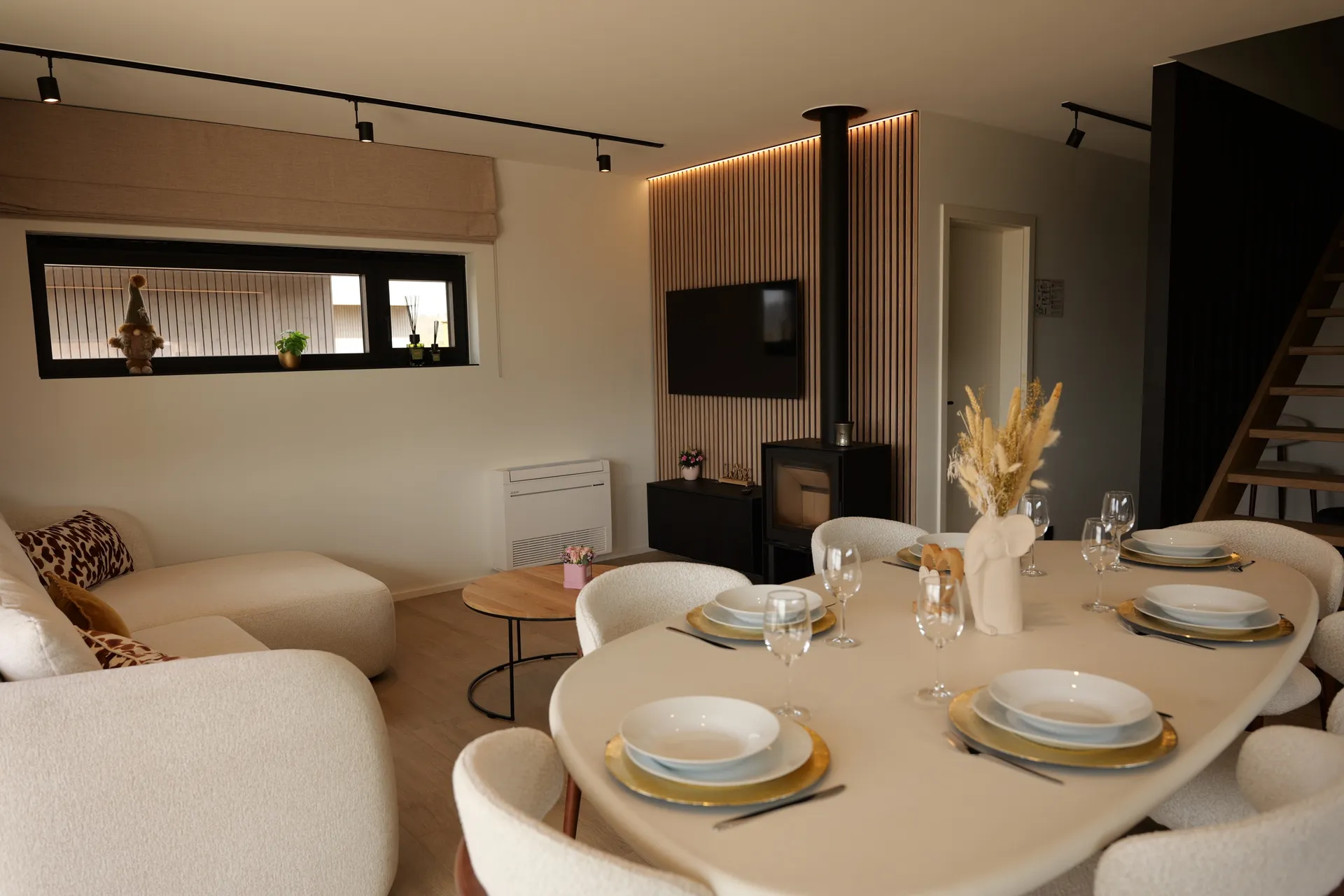 Living area with set table, sofa and wood stove in front of the slatted wall, 3-bedroom villa