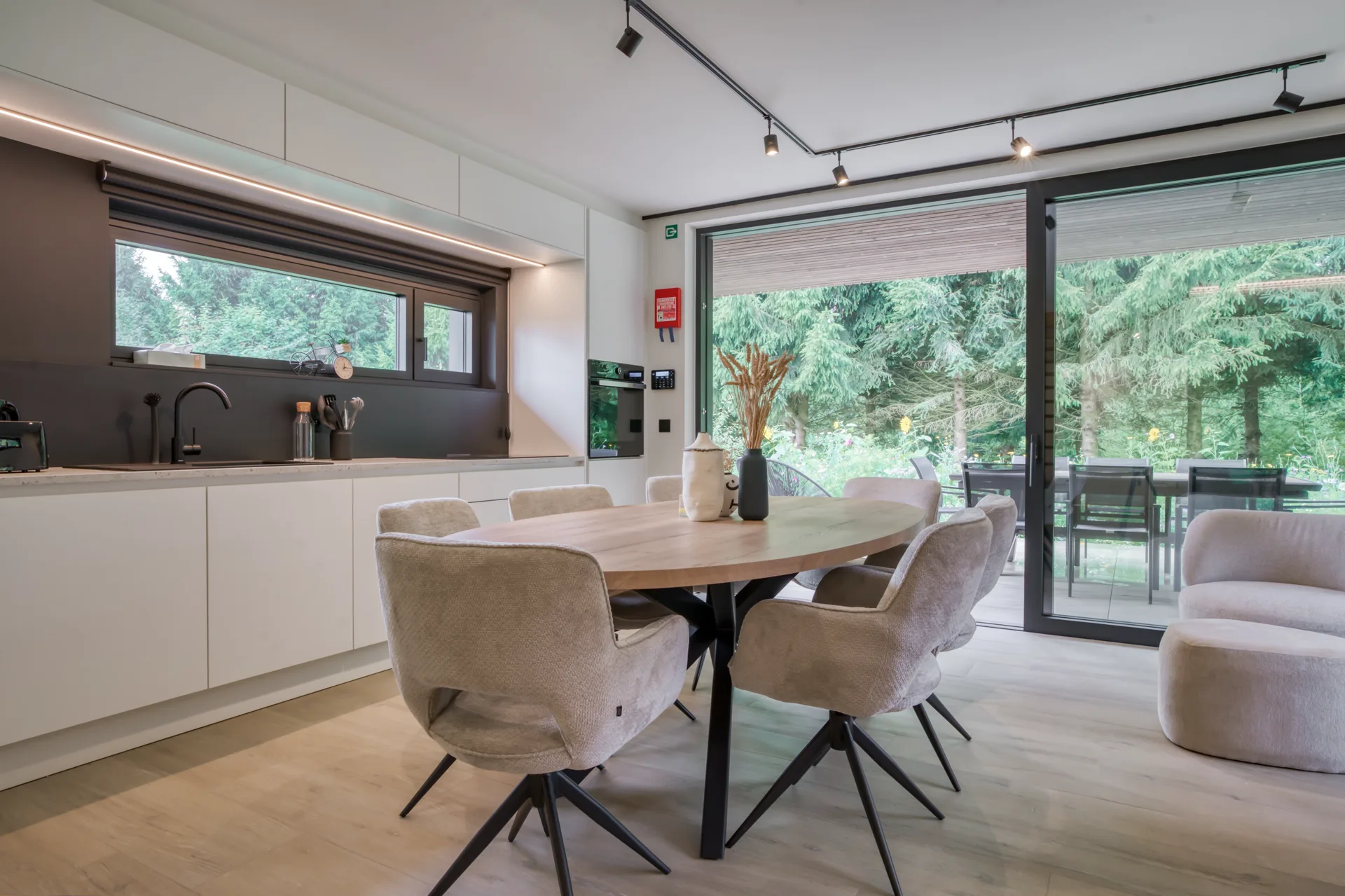 Cuisine ouverte et coin repas lumineux, grande baie vitrée sur la terrasse et la forêt, villa 4 chambres