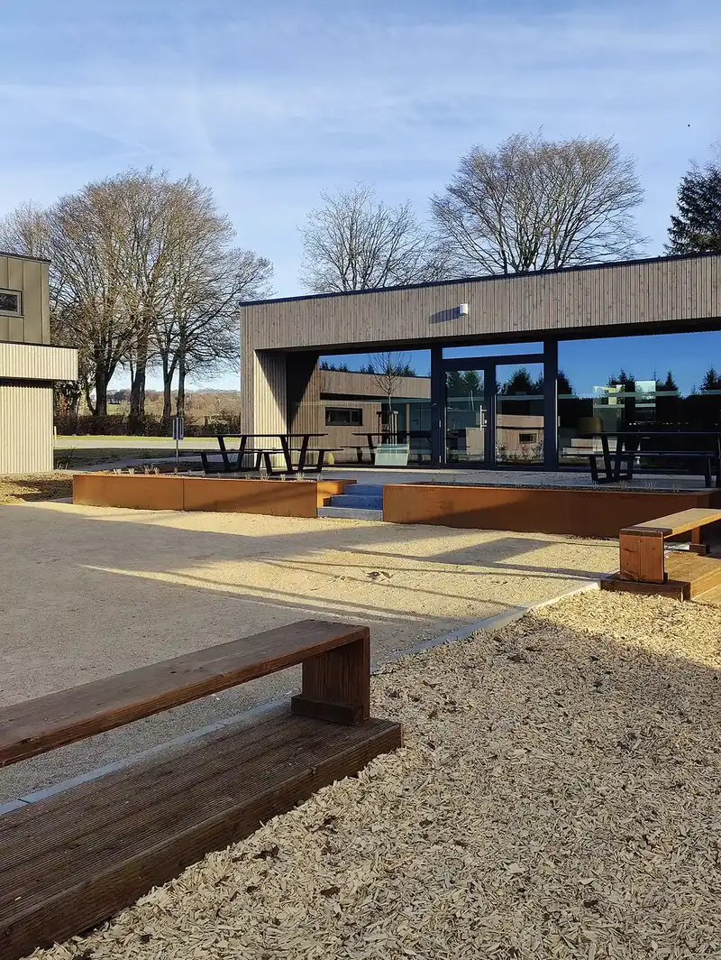 Bancs en bois et tables de pique-nique devant le bâtiment d'accueil