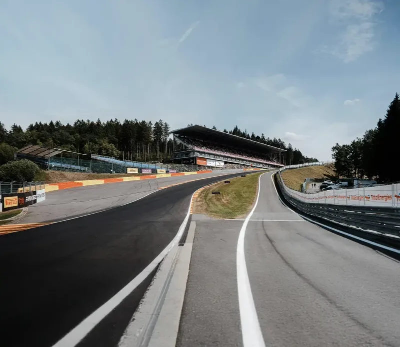 Die ansteigende Piste des Circuit de Spa-Francorchamps, große Tribüne im Hintergrund