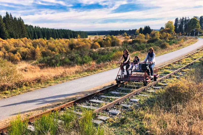 Tretdraisine auf einer alten, von Bäumen gesäumten Bahntrasse