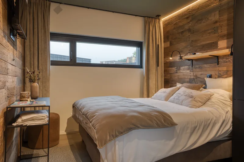 Schlafzimmer mit Fensterband, Holz-Kopfteil und Leselampen an der Wand