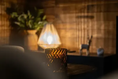 Détail lumineux : lampe tressée et objets en verre ambré sur une table basse