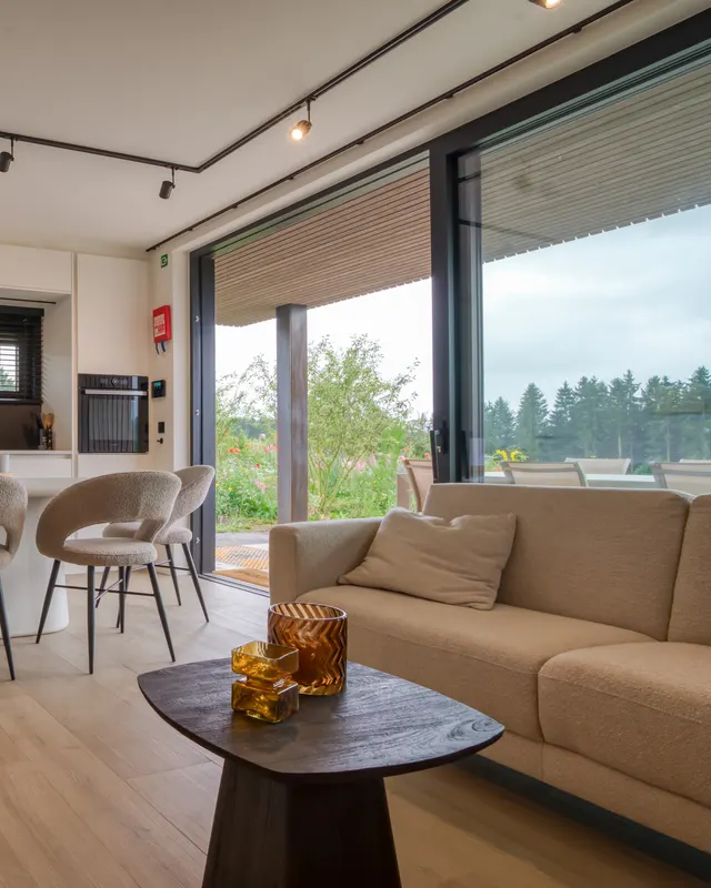 Lichtdurchfluteter Wohnraum: Essplatz und Sofa vor den Fensterfronten