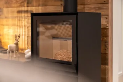 Poêle à bois moderne, bois de chauffage en réserve, mur en bois brut