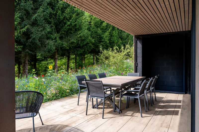 Überdachte Terrasse mit Esstisch, mit Blick auf den Tannenrand