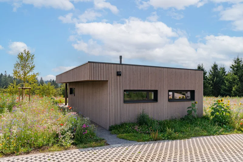 Die ebenerdige Holzvilla inmitten der Blumenwiese, am Rand des Tannenwalds