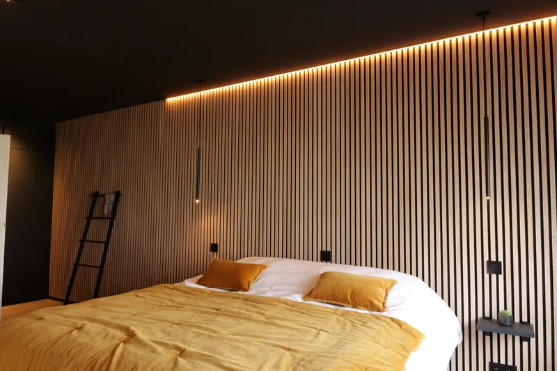 Slaapkamer met mosterdgele sprei, lattenwand en decoratieve ladder