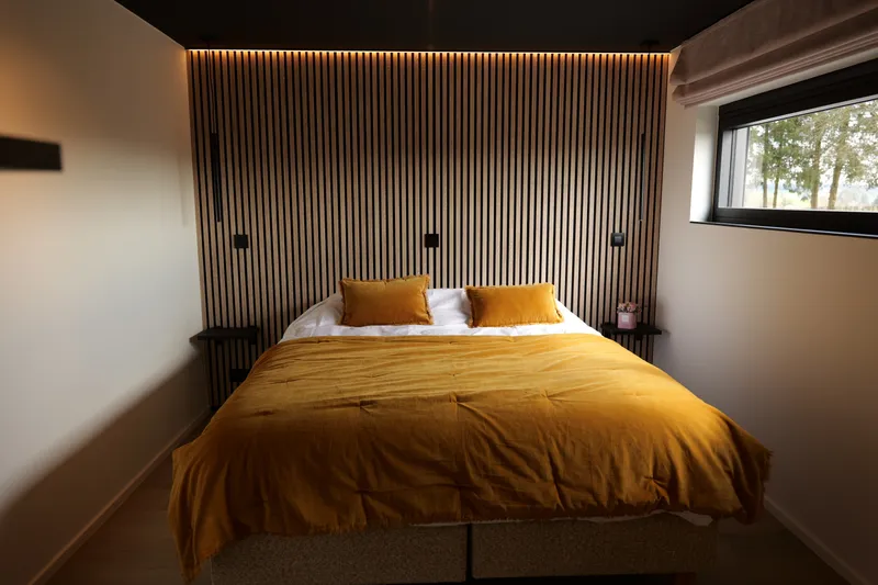 Slaapkamer met tweepersoonsbed, lattenwand en zijraam