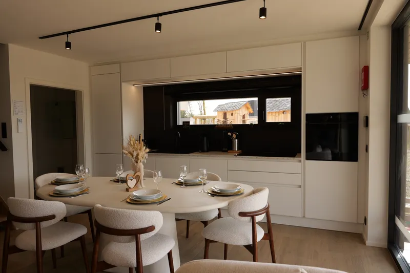 Witte ingerichte keuken met gedekte ronde tafel voor het raam