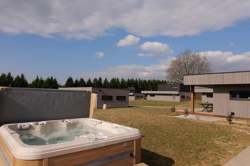 Open buitenjacuzzi aan de rand van het terras, weide en dennen aan de horizon