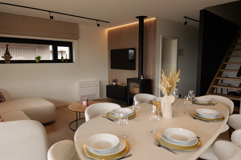 Leefruimte met zetel, houtkachel en tv aan de lattenwand
