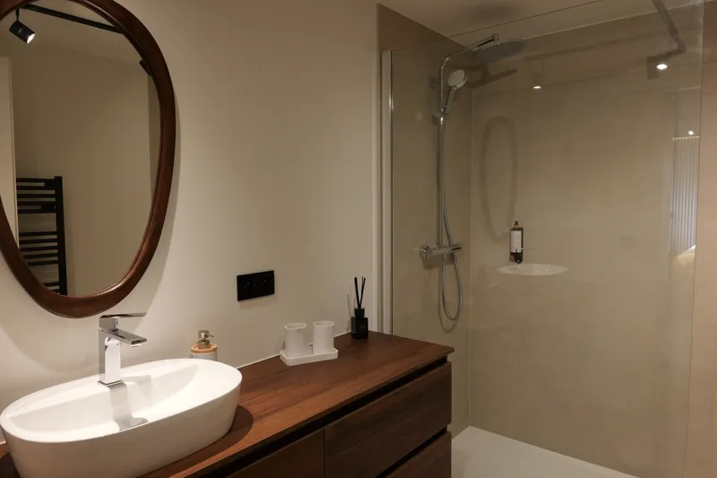 Badkamer: ovale spiegel, wastafel en inloopdouche