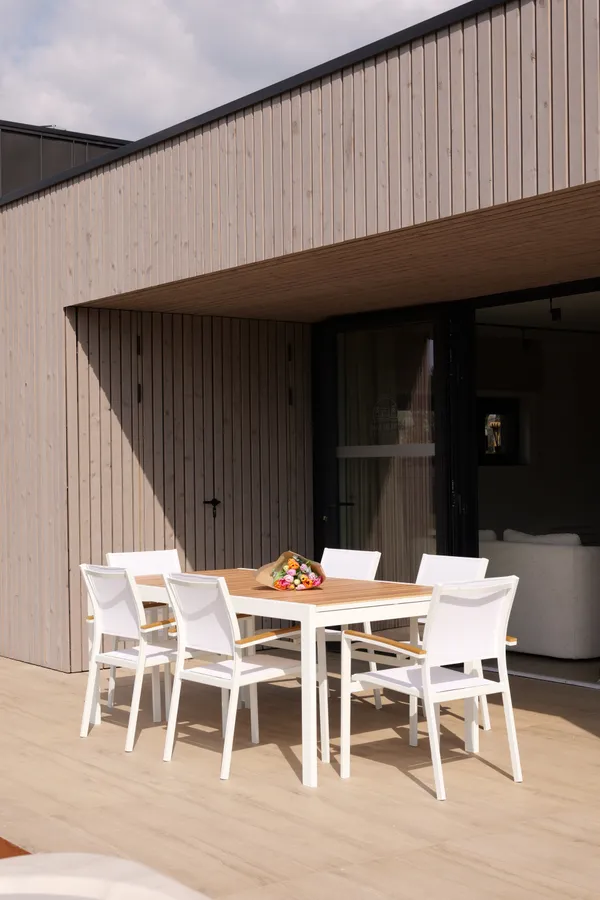 Gedekte tafel op het terras voor de houten gevel van de villa