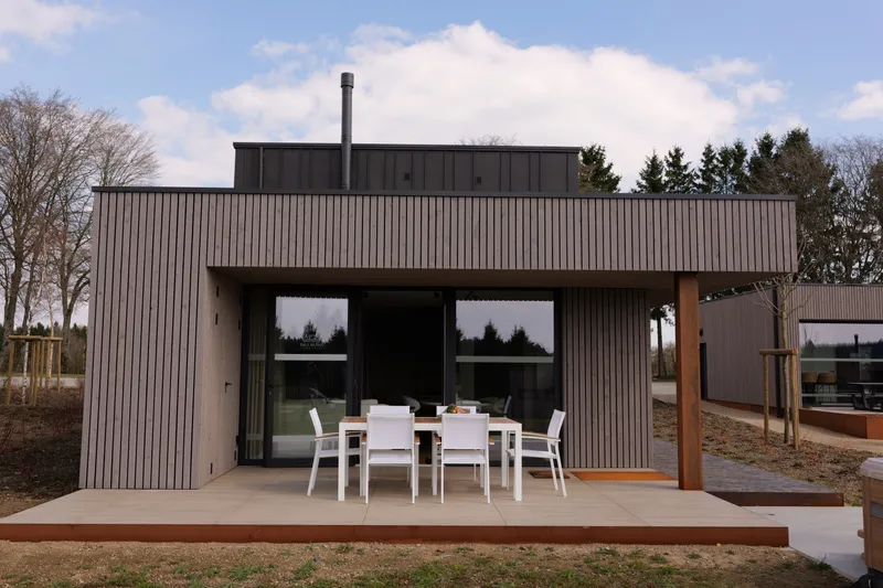 De villa in hout en zwart aluminium, overdekt terras en teruggetrokken verdieping