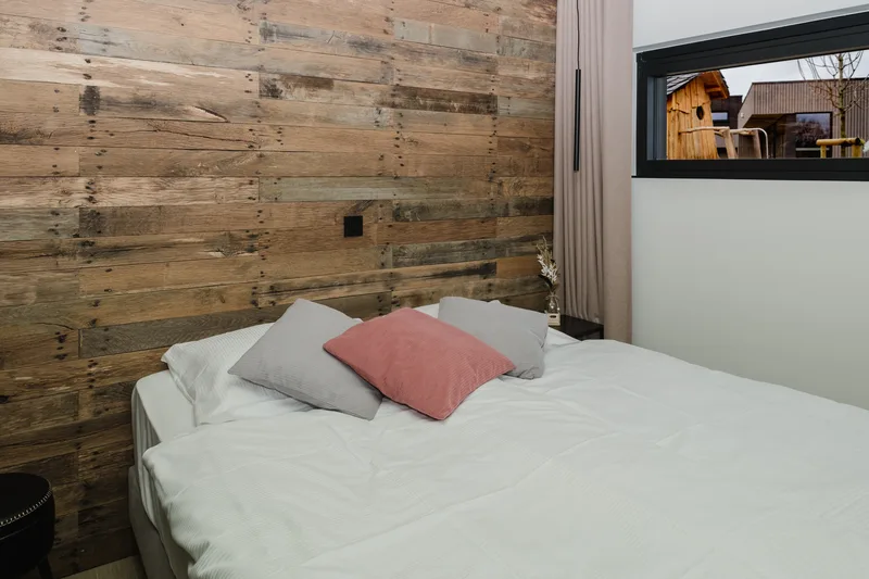 Chambre avec mur en bois de récupération, coussins et rideaux clairs