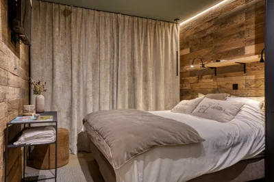 Chambre à l'ambiance tamisée, tête de lit en bois de grange et liseuses