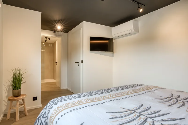 Chambre claire, linge de lit à motifs et fenêtre sur la lisière