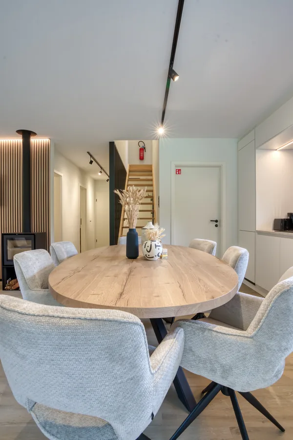 Table ronde dressée pour le dîner, escalier en bois vers l’étage en arrière-plan