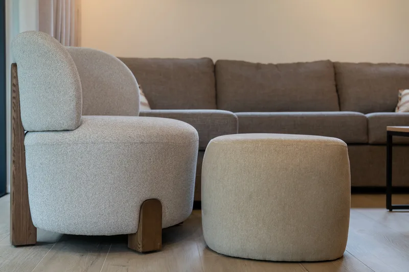 Fauteuils en tissu bouclé et pouf devant le canapé du séjour