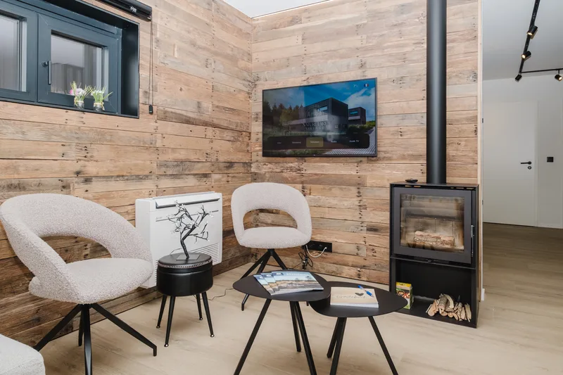 Coin salon avec fauteuils et poêle à bois, mur en bois de récupération