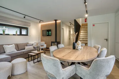 Séjour lumineux : coin salon, table à manger ronde et escalier vers l'étage, villa 4 chambres
