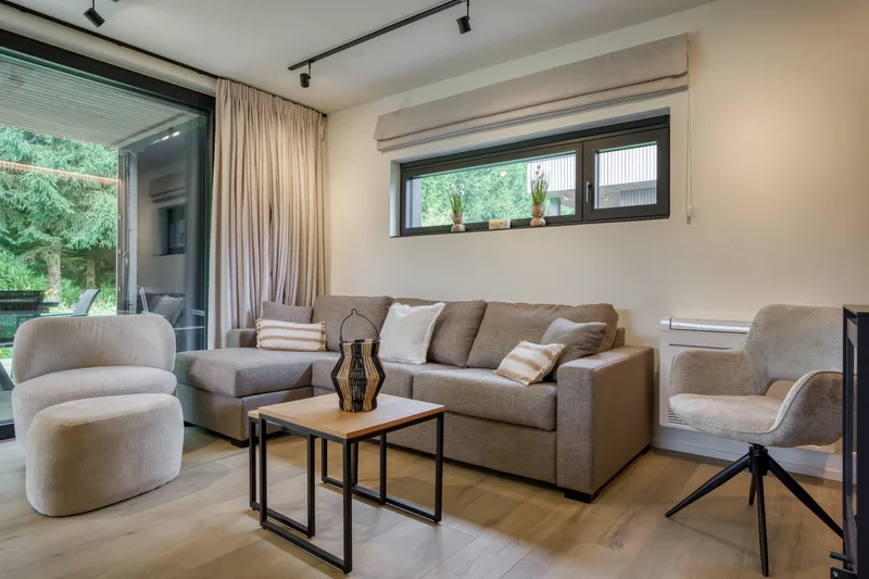 Coin salon clair avec fauteuils, table basse et baie vitrée sur les arbres