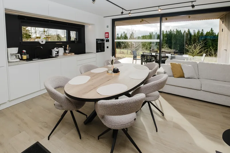Cuisine ouverte et grande table ovale, canapé et baies vitrées sur la terrasse
